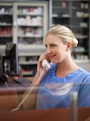 image of receptionist  - Young woman at work as receptionist and nurse in hospital and talking on the phone - JPG 