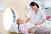 picture of health  - Radiologic technician smiling at mature female patient lying on a CT Scan bed - JPG 