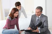 stock photo of agent  - Young couple signing renting contract with real estate agent - JPG 