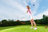 image of golf  - Young female golf player on course doing golf swing - JPG 