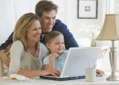 stock photo of family  - Mother and Father using a laptop with their daughter - JPG 