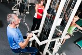 image of pulldown  - Senior people in a gym exercising on a pulldown machine - JPG 