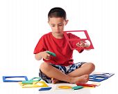 picture of puzzel  - A kindergarten boy attempting to assemble a foam puzzel of various shapes - JPG 