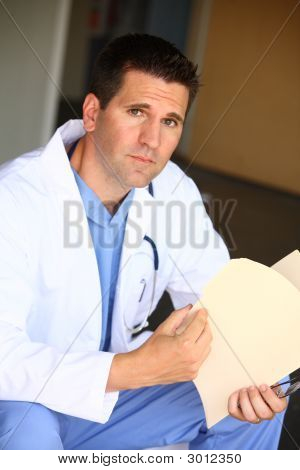Picture or Photo of Doctor looking over a patients medical records.