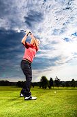 image of golf  - Young female golf player on course doing golf swing - JPG 