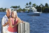 picture of past  - Happy senior man and woman couple together by a river or sea in a tropical location with a boat sailing past - JPG 