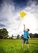 stock photo of aspiration  - Young boy flies his kite in an open field - JPG 