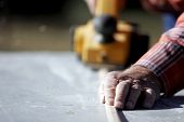 pic of construction worker  - an experienced construction worker prepares a length of wood trim for a construction - JPG 