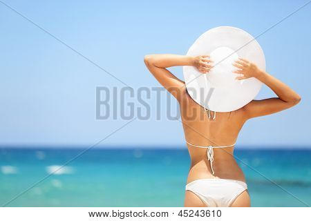 Picture or Photo of Happy woman enjoying beach relaxing joyful in summer by tropical blue water. Beautiful bikini model happy on travel wearing beach sun hat on Hapuna beach, Big Island, Hawaii, USA.