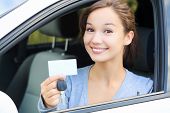 foto of transportation  - Happy girl in a car showing a key and an empty white card for your message - JPG 