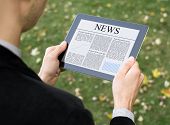picture of newspaper  - Businessman reading news on digital tablet at park - JPG 