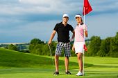 stock photo of golf  - Young sportive couple playing golf on a golf course - JPG 