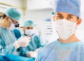 stock photo of teamwork  - Male surgeon with two doctors on background in operation room - JPG 