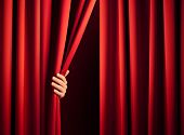 image of opulence  - male hand in the act of disclose the scene shifting the red curtain - JPG 