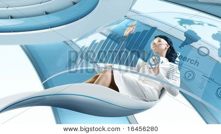 Picture or Photo of Future lifestyle. Sexy brunette sits in the futurisctic armchair. Working with transparent touch screen interface. Concept of computer operator workplace in the future / space ship or another planet.
