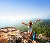 stock photo of valley  - Young backpacker standing on top of a mountain and enjoying a morning valley view - JPG 