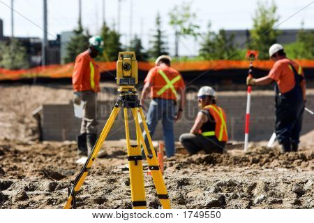 Picture or Photo of Theodolite on a tripod with construction workers in the background.