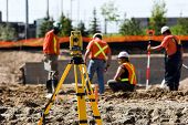 picture of construction worker  - Theodolite on a tripod with construction workers in the background - JPG 