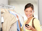 picture of woman  - Modern woman shopping looking at smartphone texting or talking smiling happy in clothes store - JPG 
