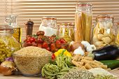 pic of food  - A display of healthy foods including various vegetables jars of pasta rice seeds onions garlic olive oil aubergine tomatoes peppers spaghetti and courgettes - JPG 