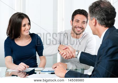 Picture or Photo of Happy couple seal a deal with their personal financial advisor at home