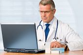 stock photo of medical doctors  - Mature doctor working on laptop and medication - JPG 