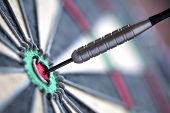 foto of on target  - Dart in bulls eye of dartboard with shallow depth of field concept for hitting target - JPG 