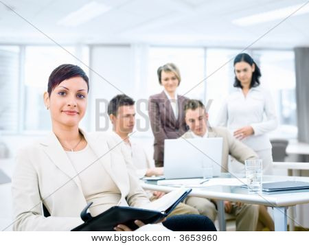 Picture or Photo of Group of five young business people working at office with businesswoman sitting in front.