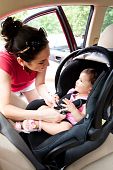 pic of seating  - Happy smiling mother placing baby in car seat and closing belt for safety - JPG 