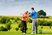 stock photo of golf  - Young female golf player at Driving Range with a Golf Pro - JPG 