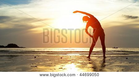 Picture or Photo of Silhouette young woman, exercise on the beach at sunset.