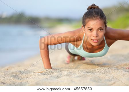 Picture or Photo of Push-ups fitness woman doing pushups outside on beach. Fit female sport model girl training crossfit outdoors. Mixed race Asian Caucasian athlete in her 20s.