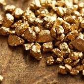 stock photo of tough  - a mound of gold on a old wooden work table - JPG 