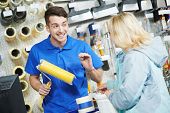 foto of hardware  - Assistant seller help buyer by demonstrating paint roller for painting at hardware store - JPG 