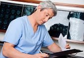 pic of medical doctors  - Mature male medical professional in uniform going through document at clinic - JPG 