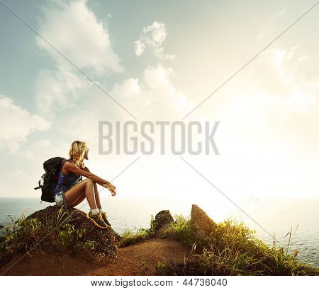 Picture or Photo of Hiker with backpack relaxing on a rock and enjoying sunset