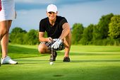 stock photo of fitness  - Young golf player on course putting - JPG 