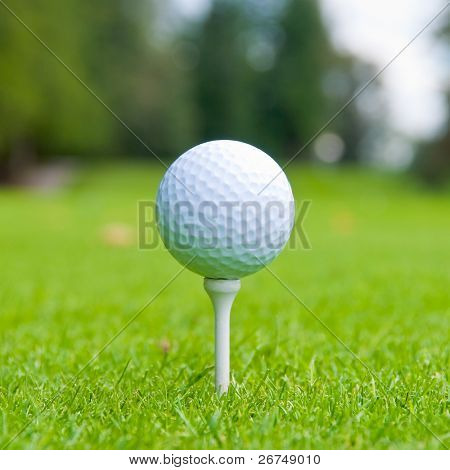 Picture or Photo of Golf ball on tee over a blurred green. Shallow depth of field. Focus on the ball.