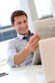 picture of newspaper  - Businessman reading newspaper in office - JPG 