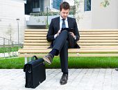foto of businessmen  - Young businessman using a tablet on a bench in the city - JPG 