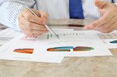 stock photo of investment  - Businessman Analyzing Investment Charts at His Workplace - JPG 