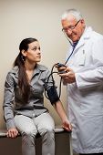 picture of pressure  - Senior male doctor checking blood pressure of young woman - JPG 