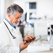 pic of computer  - Senior doctor using his tablet computer at work  - JPG 