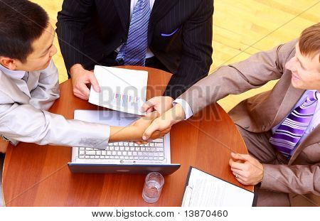 Picture or Photo of Business handshake over workplace