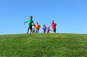 image of blue sky  - Group of kids running on grass hill with blue sky - JPG 