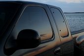 foto of tint  - American black truck parked at the beach with a sunset reflection in the tinted window - JPG 