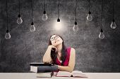 stock photo of symbols  - Portrait of smart female college student with books and bright light bulb above her head as a symbol of bright ideas - JPG 