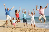 foto of holidays  - Portrait Of Three Generation Family On Beach Holiday Jumping In Air - JPG 