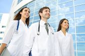 stock photo of medical doctors  - Group of happy young doctors go along a modern building of hospital - JPG 