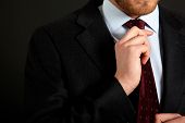 stock photo of businessmen  - Businessman adjusting his look on a dark background - JPG 